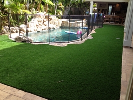 back yard pool with surrounding artificial turf